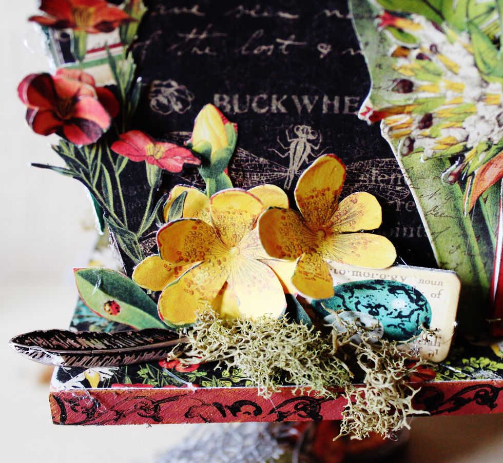Fussy cut flowers from pattern paper, roll on soft mat with stylus. Add to front of birdhouse with moss, metal feather and chipboard piece.