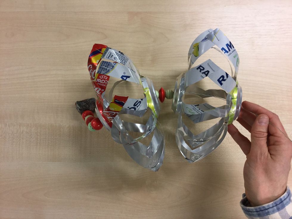 G\u00f6r en till vindsnurra av tv\u00e5 burkar (steg 1-12). Tr\u00e4 den p\u00e5 st\u00e5ltr\u00e5den. V\u00e4lj om snurrorna ska snurra \u00e5t samma eller olika h\u00e5ll genom att tr\u00e4 p\u00e5 den \u00e5t samma eller motsatt h\u00e5ll som den f\u00f6rsta snurran.