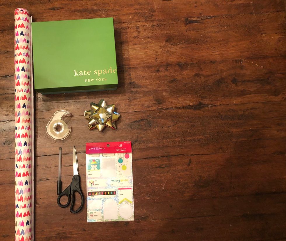 Gather all of the materials that you need to wrap your present. You will need wrapping paper, your present, tape, scissors, a bow, a pen, and name tags.