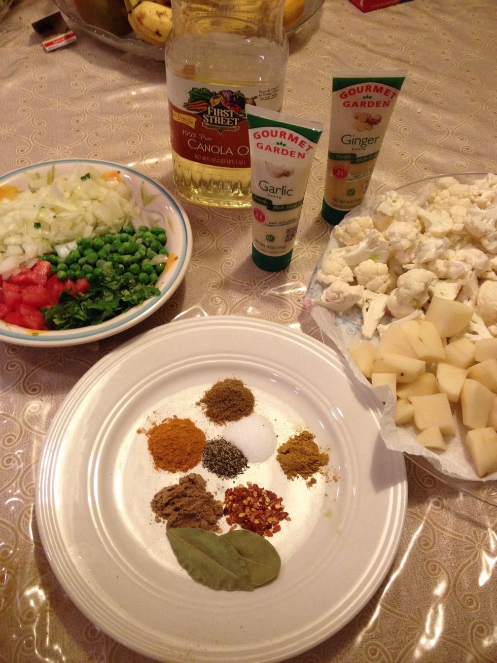 Gather all of your ingredients. Chop one head of cauliflower and 5-6 potatoes into bite-size pieces. Dice 1/2 an onion, 1 tomato, and a pinch of cilantro..then set aside.