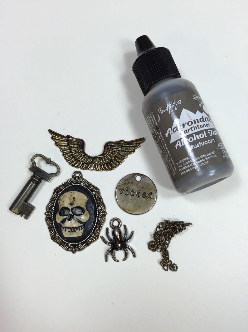 Gather metal findings you'd like to use. These are various pieces from Tim Holtz's Idea-ology line. Dab Mushroom alcohol ink on each piece to give them an aged look. Let dry or use a craft dryer.