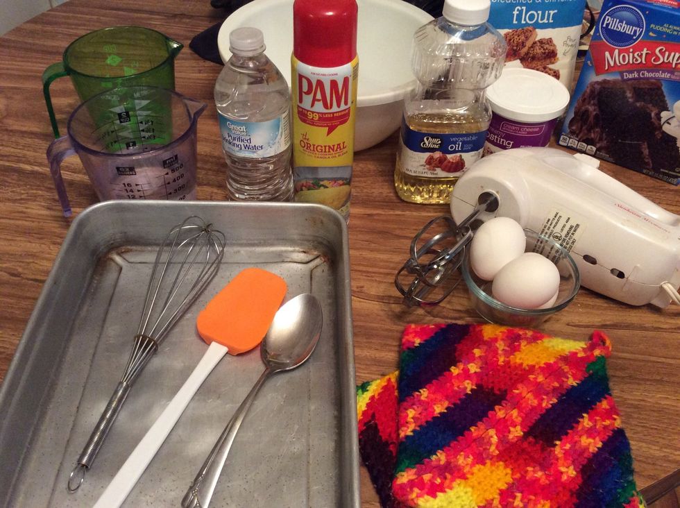 Gather supplies \n\nMeasuring cups \nA cup of Water \nCake mix\n1/2 cup of Vegetable Oil \nA cake pan\nAn oven \n3 eggs \nMixer/ whisk \nMixing bowl\nPot holders / oven mitts\nButter knife \nA rubber scraper \n\n