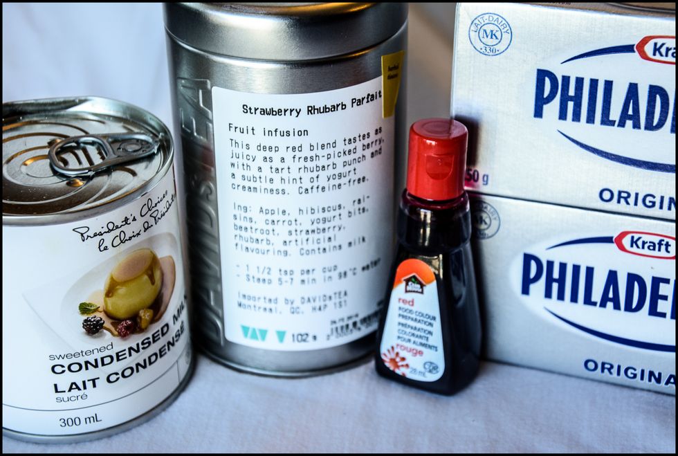 Gather the ingredients for the cheesecake: DAVIDsTEA "Strawberry Rhubarb Parfait", sweetened condensed milk, two packages of cream cheese at room temperature and red food colouring (optional).