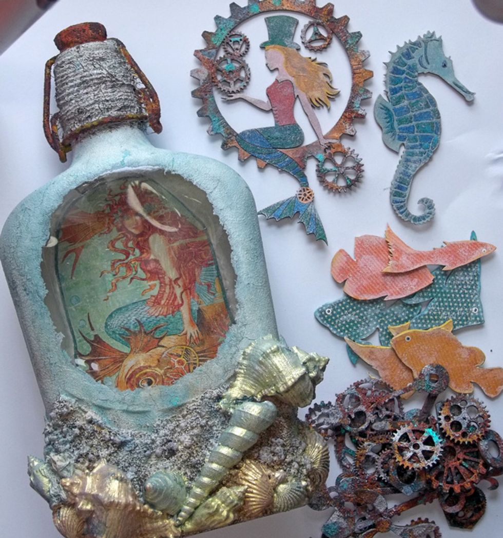 Gather your chipboard elements and strong glue and start adding them to the altered bottle.