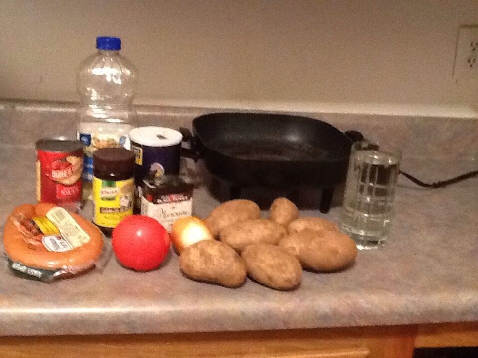 Gather your ingredients 7 potatoes, 1 thing of smoke sausage, 1 onion, 1 tomato, beef flavor, oil, salt and pepper, and 1 big pan