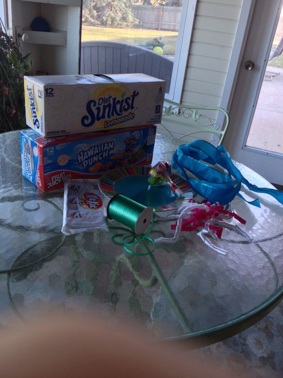 Gather your ingredients; eight pop or juice cans, a dinner plate, two ribbons, a piece of duct tape, a rubber band, candy bars, and a bow (optional)