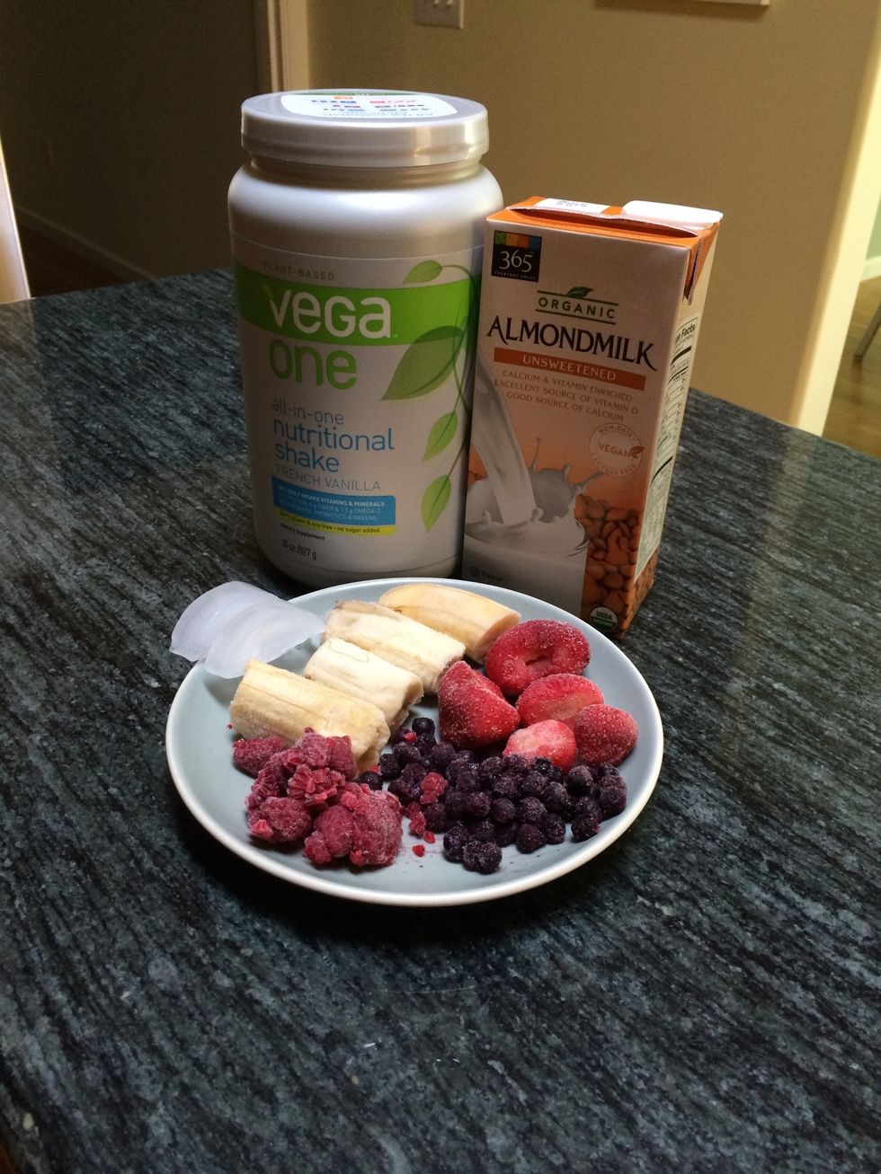 Gather your ingredients: vega one protein powder, almond milk, ice, frozen fruit (banana, strawberries, raspberries, blueberries)