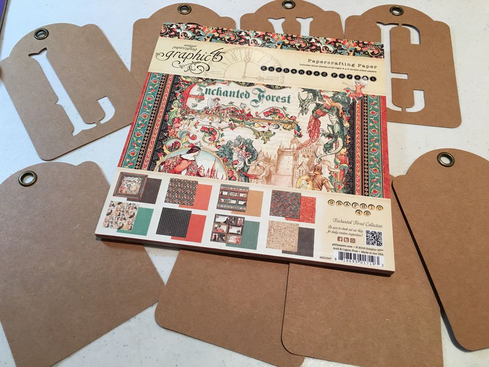Gather your supplies together including the 8x8 Graphic 45 Enchanted Forest Paper Pad, Graphic 45 Alpha Banner Tags to spell "LOVE" and blank kraft Graphic 45 Square Tags.