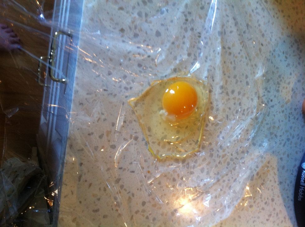 Gently, crack the egg onto the middle of the cling wrap