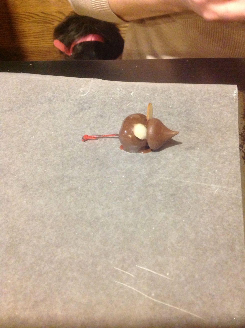 Gently push a kiss on the from and push two ear shaped almonds between them. If you need to, dip the almond slice in chocolate then add it.