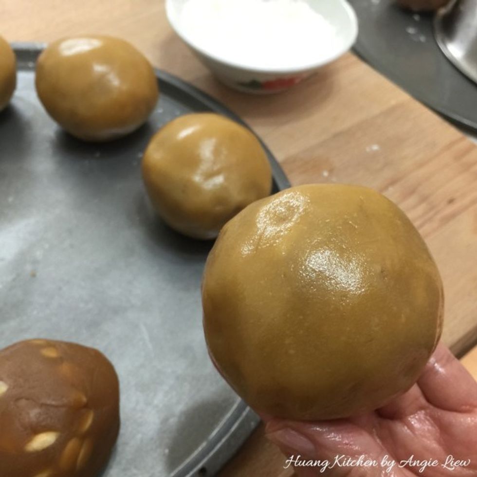 Gently push, press & squeeze the dough, holding the it securely in your palm, until the dough skin gradually covers lotus paste ball. Repeat this step on remaining dough skin and lotus paste balls.