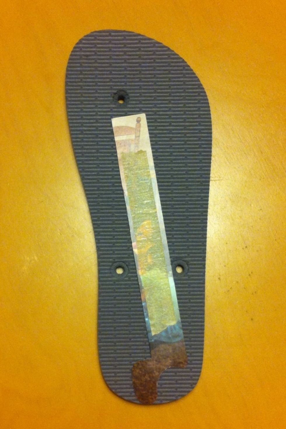 Gently remove the strap from the flip flop. Align the first paper template from the heel to the hole between the toes, getting the most length possible without hitting one of the holes.
