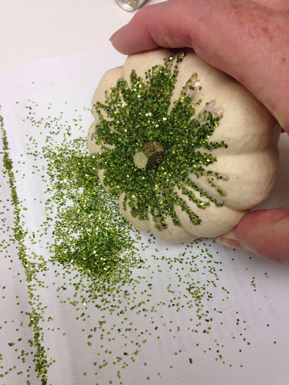 Gently tap the pumpkin on your work surface to get the extra glitter off. You can use your scrap paper to pour the extra glitter back into its' container for a different project.