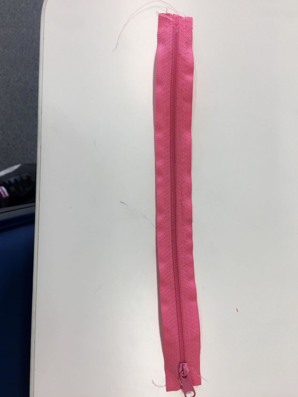 Get a 18cm long zipper and starting sewing it to the pouch
