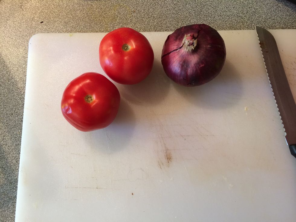 Get a chopping board and prepare the tomatoes and onion.