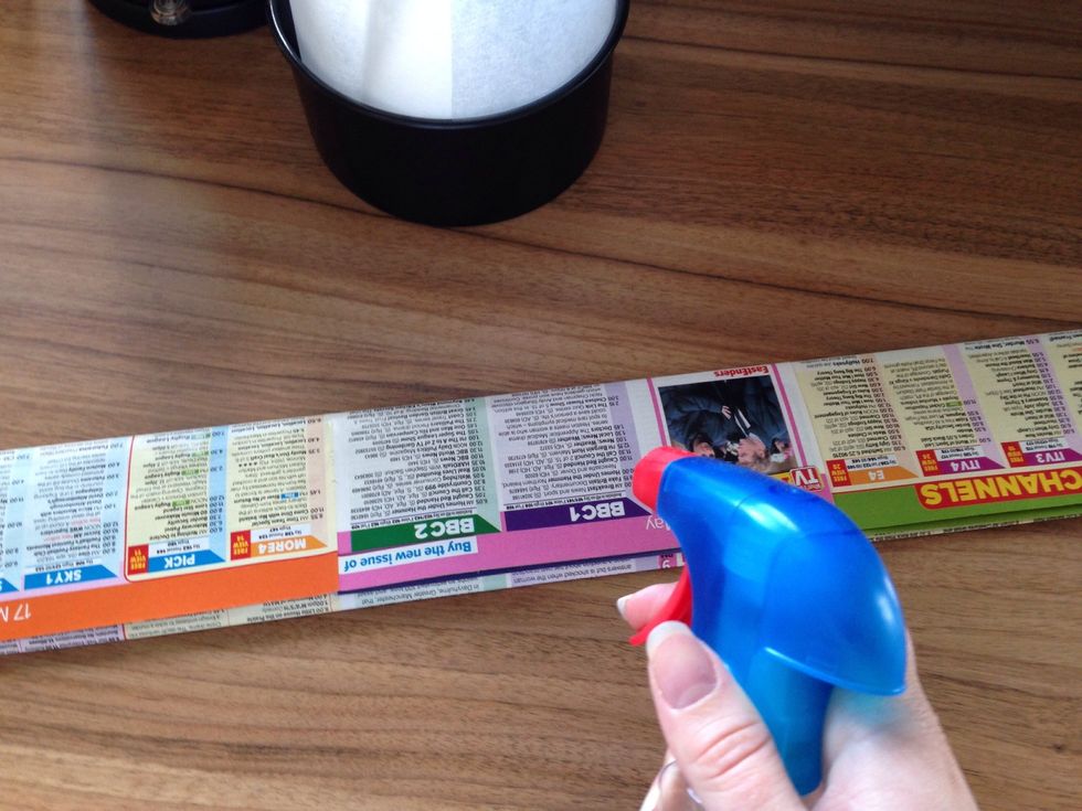 Get a couple of pages from an old magazine or newspaper. Make sure its long enough to wrap around the tin. You might have to tape a few pages together. Spray with some water until it is fairly damp.