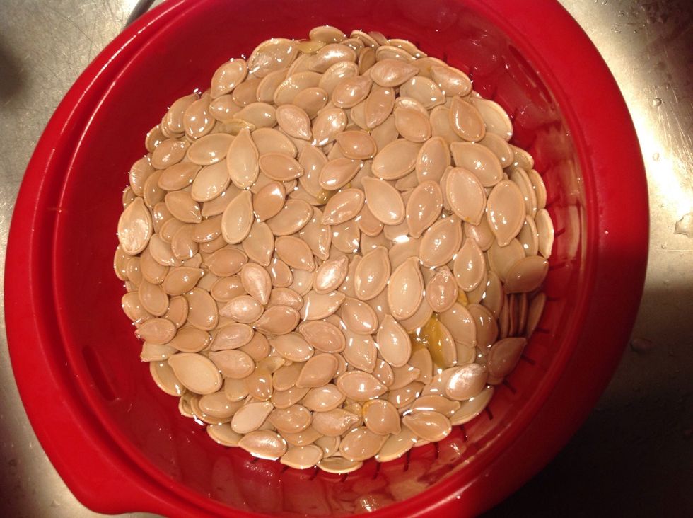 Get a fruit strainer and wash the seeds. Try your best to get the pumpkin gut out.