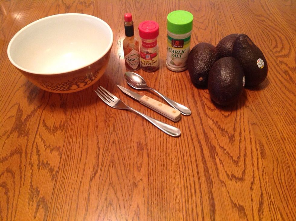 Get a knife, a spoon, a fork, 3-6 avocados, a large bowl, crushed red pepper flakes, garlic salt and Tabasco sauce.
