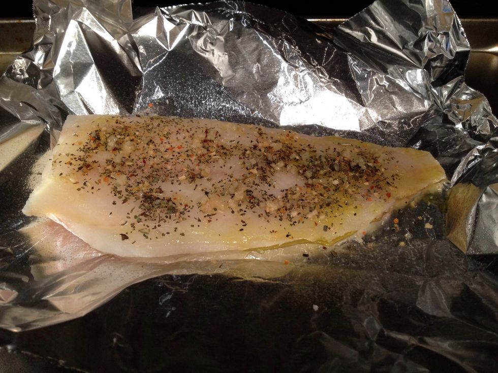 Get a large piece of foil, slap some olive oil on there, and then rub the fish down with more olive oil. Sprinkle it with salt, pepper, basil, and the garlic.