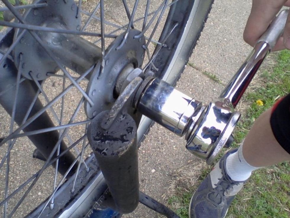 Get a socket wrench that fits the size of the lug nuts on the front tire.