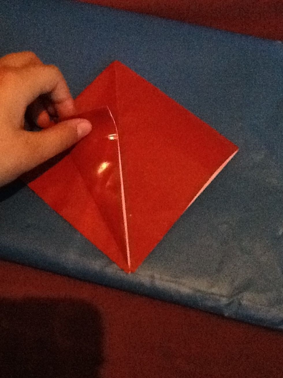 Get one flap now and fold it so it meets with the middle crease.