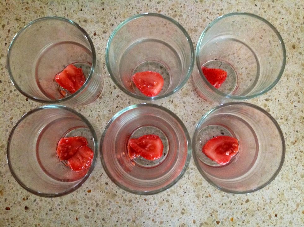 Get six glasses out and place a strawberry (that you out aside) at the bottom of each.