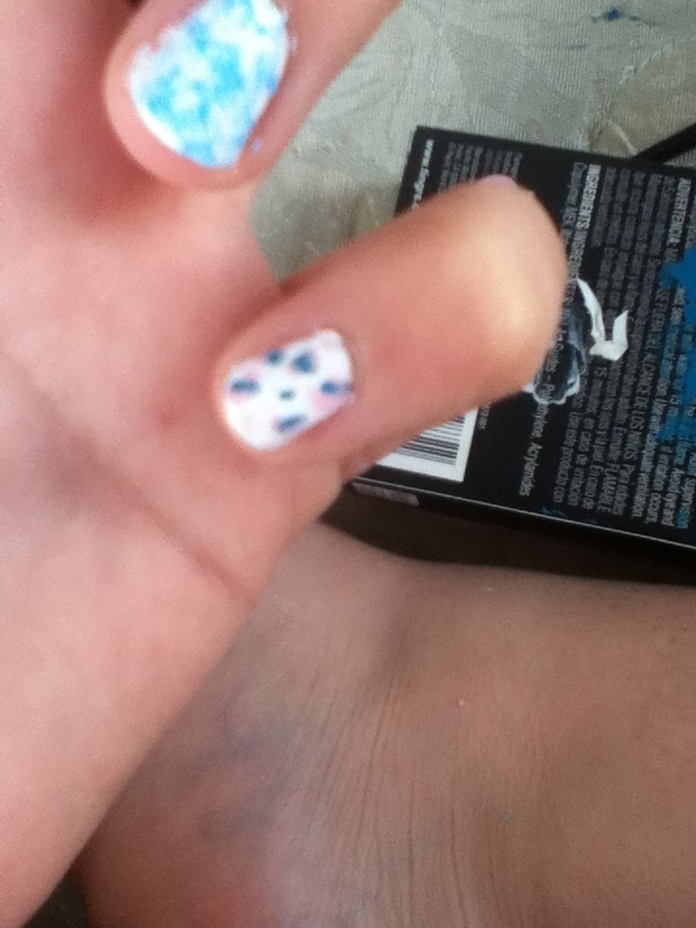 Get small brush and make dots outside of the blue ones and dots all around finger