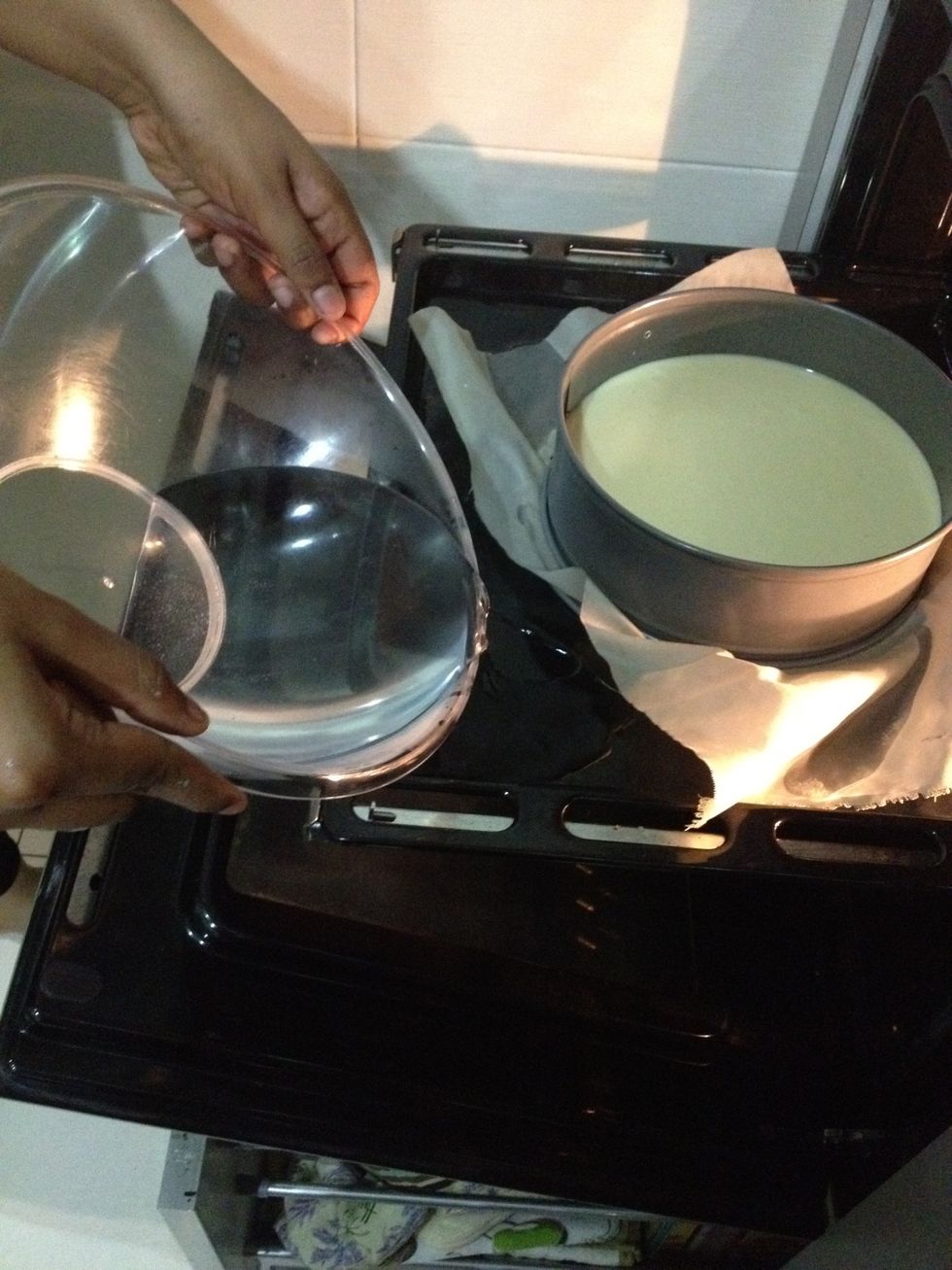 Get some hot water and pour it into your big tray which your cake is on. This is called water bath so that the cake cooks as even as possible. Bake for 1 hour at 160\u00b0C/320\u00b0F.