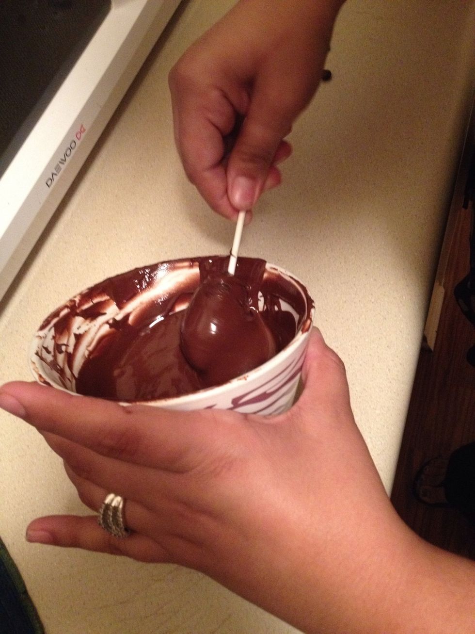 Get the cake pops into the melted candy coating. Make sure the coating is deep enough to get the entire cake pops, w/ ears attached, submerged in one dunk.
