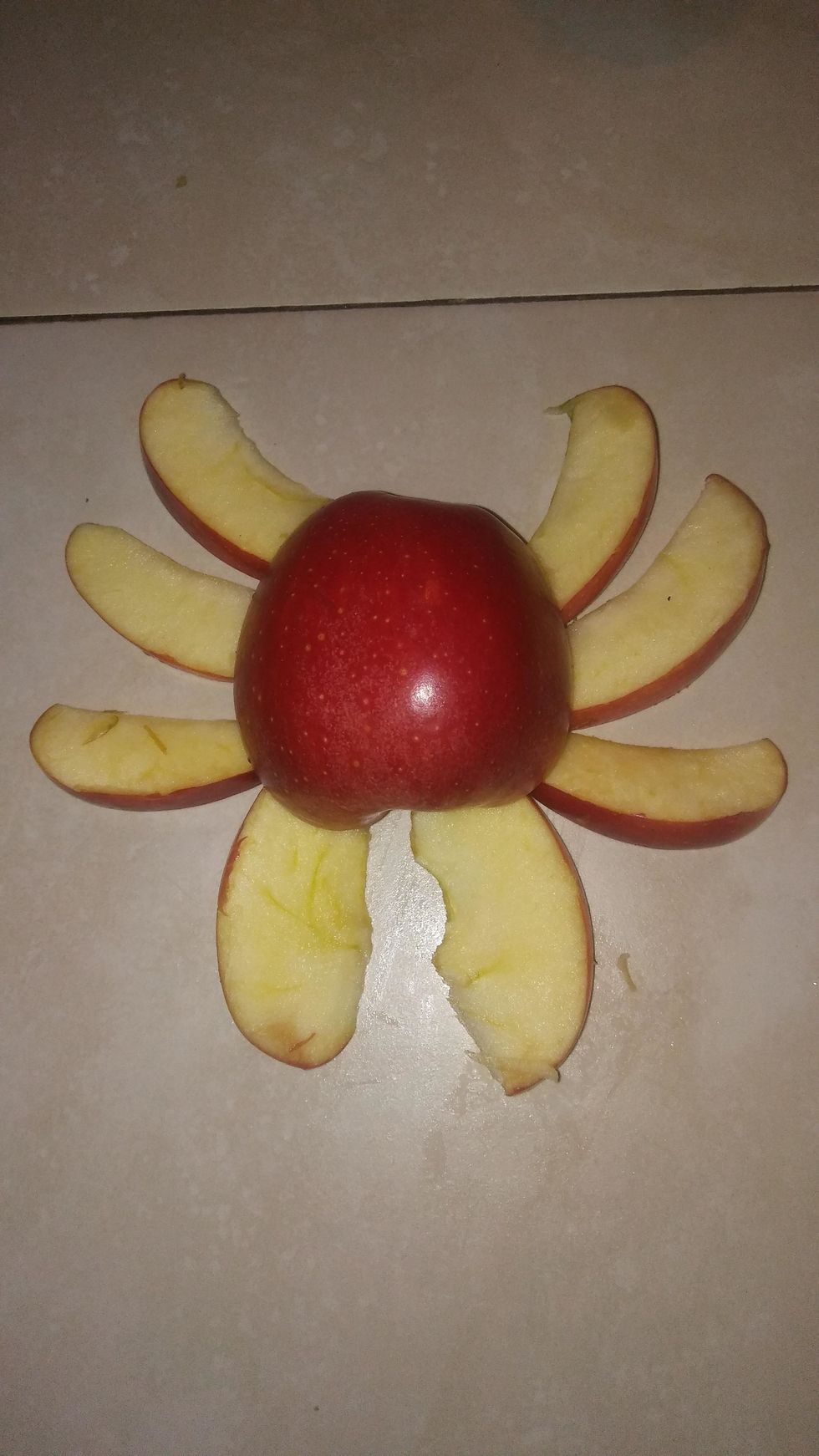 Get the eight pieces and place them on your surface like so, and place the other half of the apple that you haven't used on top of the pieces. And use two of your pieces as the pinchers of your crab.