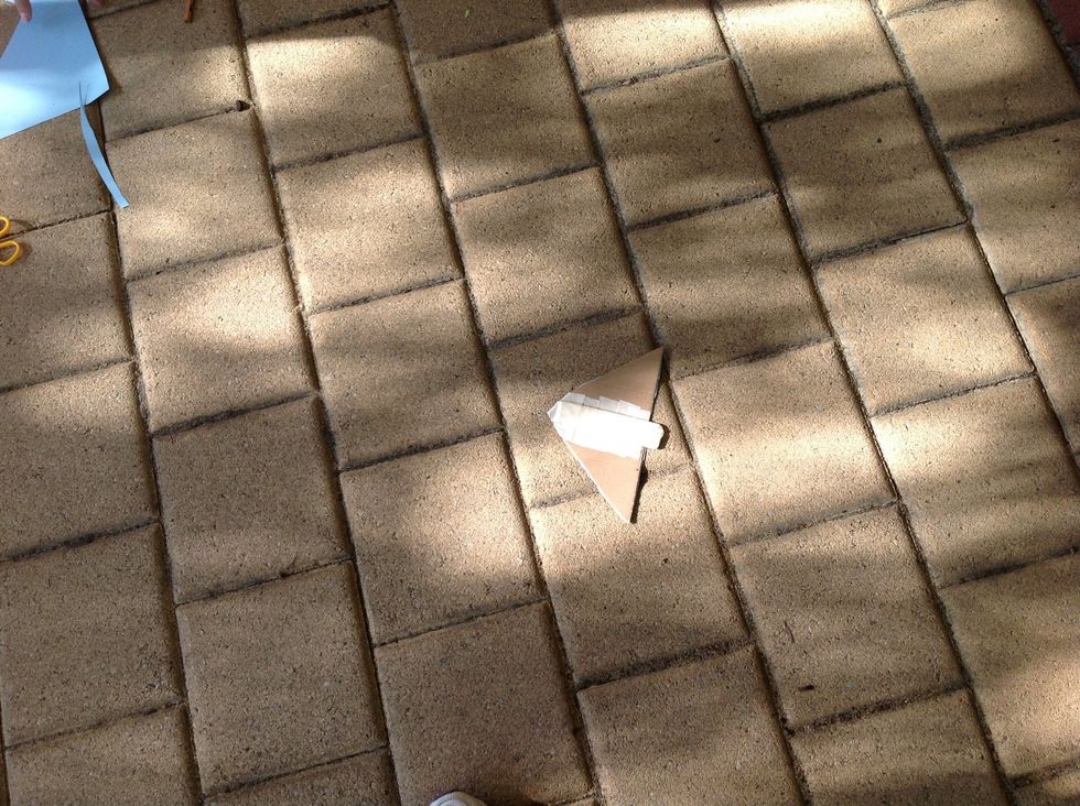 Get the popsticks and the card and place the popstick in the middle of the your glider on the side that you haven't covered. Stick it down with masking tape.