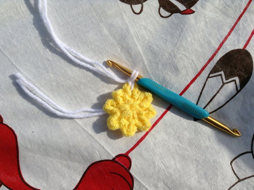 Get the white yarn and join it with a sl st to any of the 8 loops on your flower.