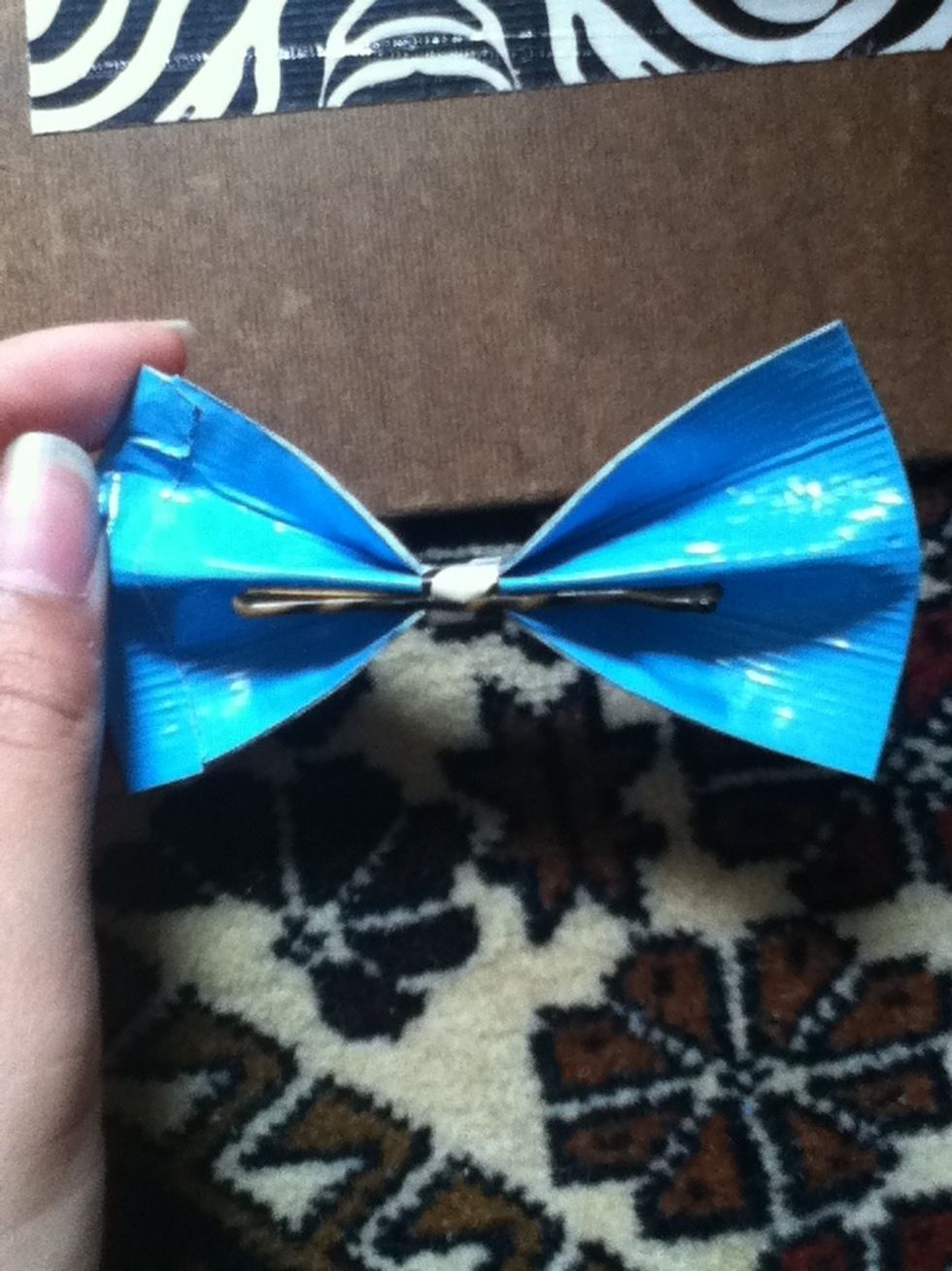 Get your bobby pin and slide it in between the backside of the strip of tape you just put on. Like this: