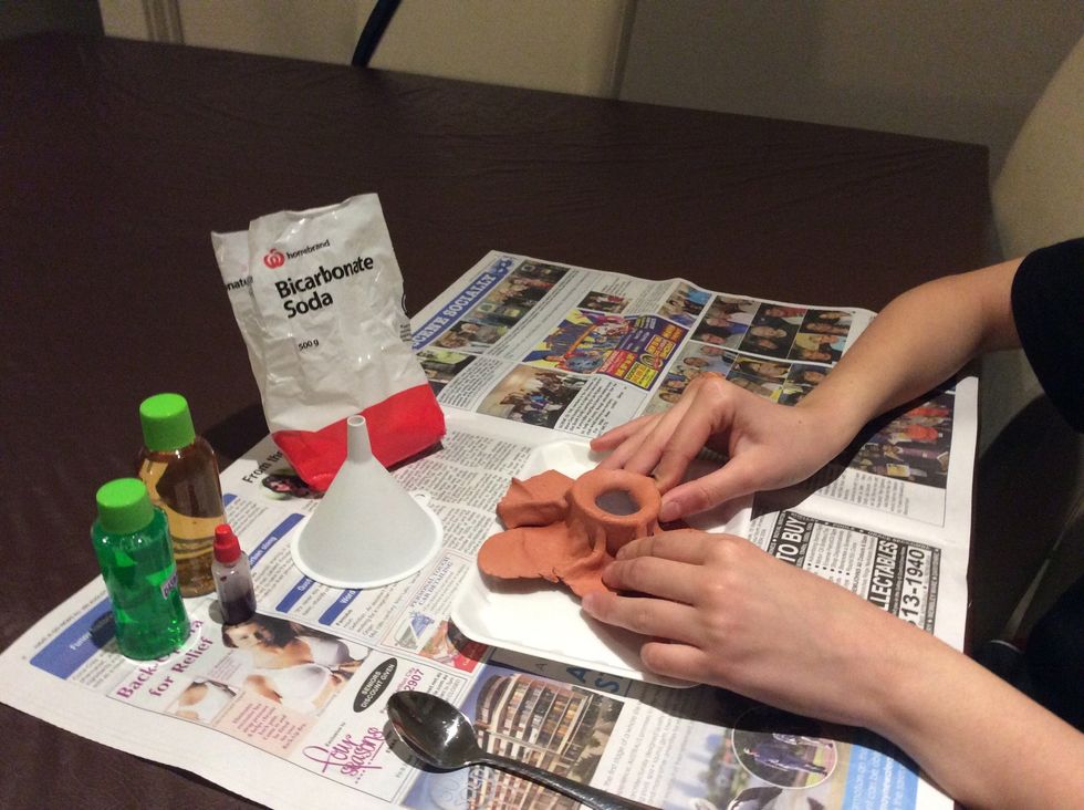 Get your clay and start modelling over your container with it. (Tip: because this is a volcano, try and mould a volcano shape, just like I did!)