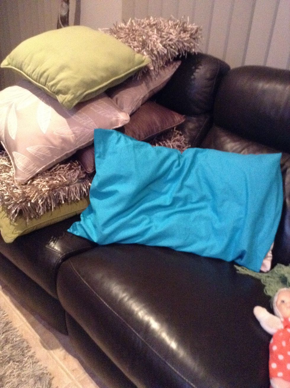 Get your first big pillow and put it into a corner on the couch next to he small pillows.
