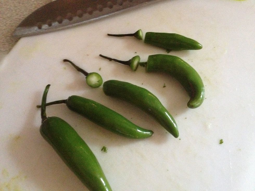 Get your Serrano peppers and cut the top part, you won't need it.  If you want it spicier, just add them like this to the blender. If not, open them and take out the seeds, let me show you how.