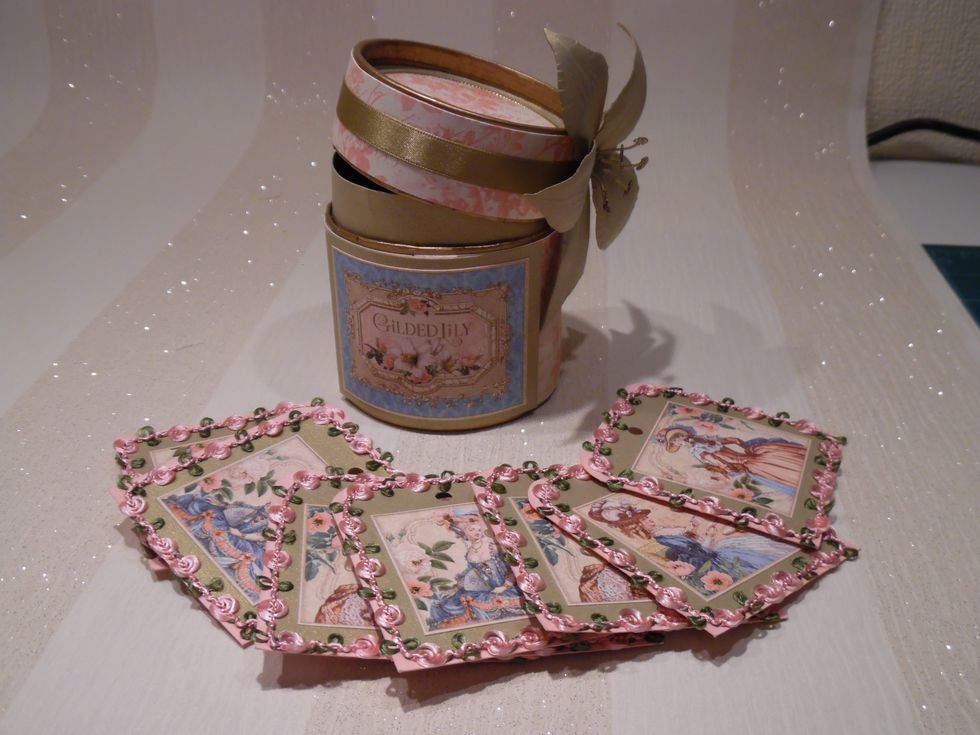 Gilded Lily papers used to decorate container. Tags cut from gold card. Cameos added and trimmed with pink rose braid.