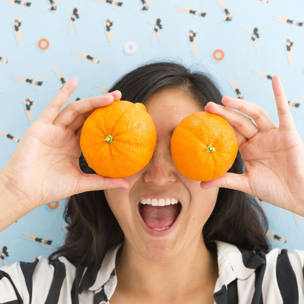 girl holding up oranges which are similar to yuzus to her eyes