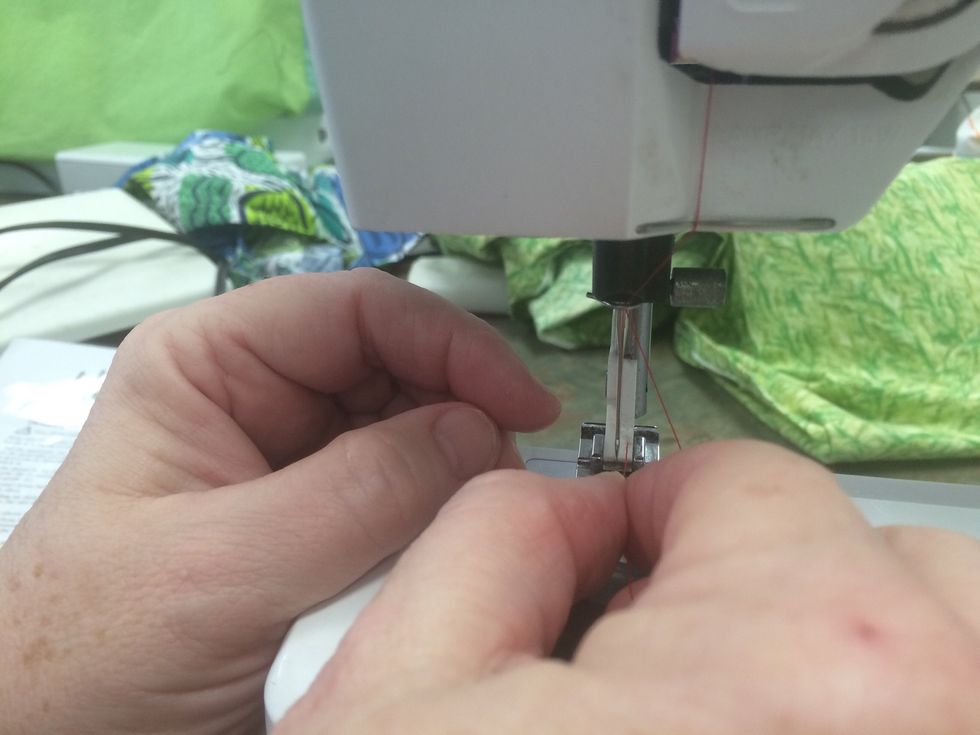 Gliding from front to back, place the thread through the eye of the needle