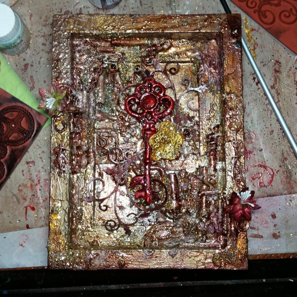 Glue 2 red flowers to the sides with molding pate. See if the red key, flourishes, and gold flower work together (have not glued them yet).