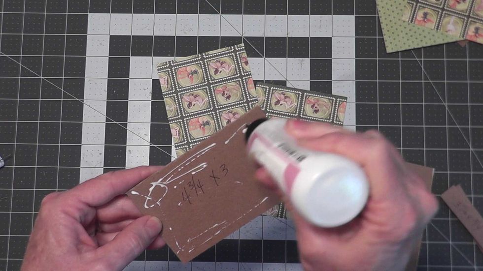 Glue a 4 3/4" x 3" chipboard piece to the BACK side of a 4" x 5 3/4" piece of paper, centered side to side and top to bottom. You will make two of these for your covers.
