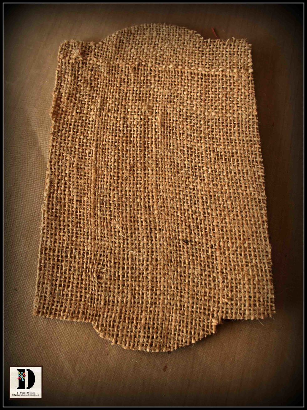 Glue a piece of burlap to the chipboard banner panel and trim around the edges.