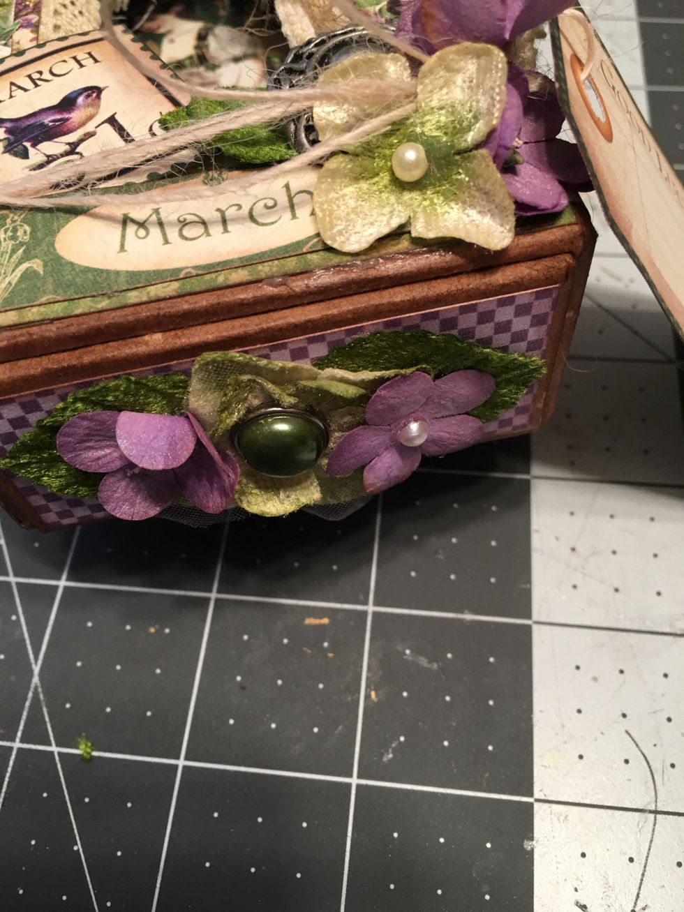 Glue assorted leaves, flowers and a green pearl brad to the front side of the slide in tray. (Only on one end which would be the bottom end of the tray.)