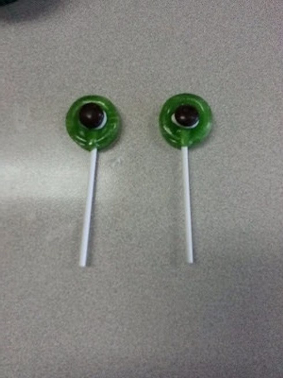 Glue brown m&ms onto a lollipop using a small dollop of icing. Repeat this step to make two eyes