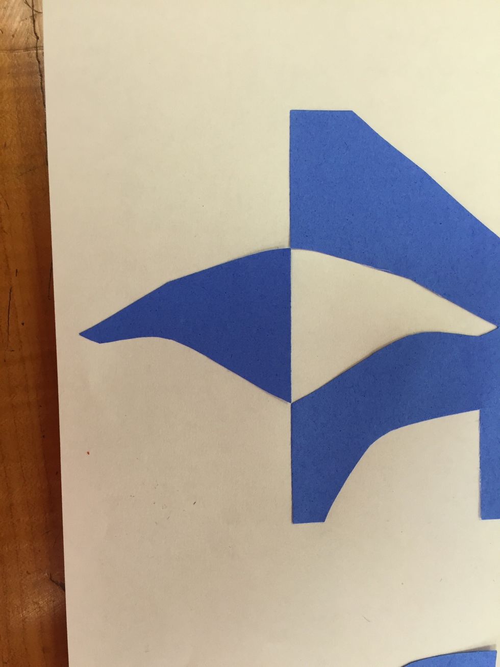 Glue down the cut shapes so that they create symmetry with the negative space beside them. Negative space is the colored portion, positive space is the white portion.