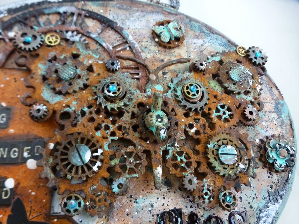 Glue down your metals and chipboard using E600. Add bling to make it spark. I used a chalk edger to darken some random spots. The wing nut in the center is a resin piece that I painted and inked.