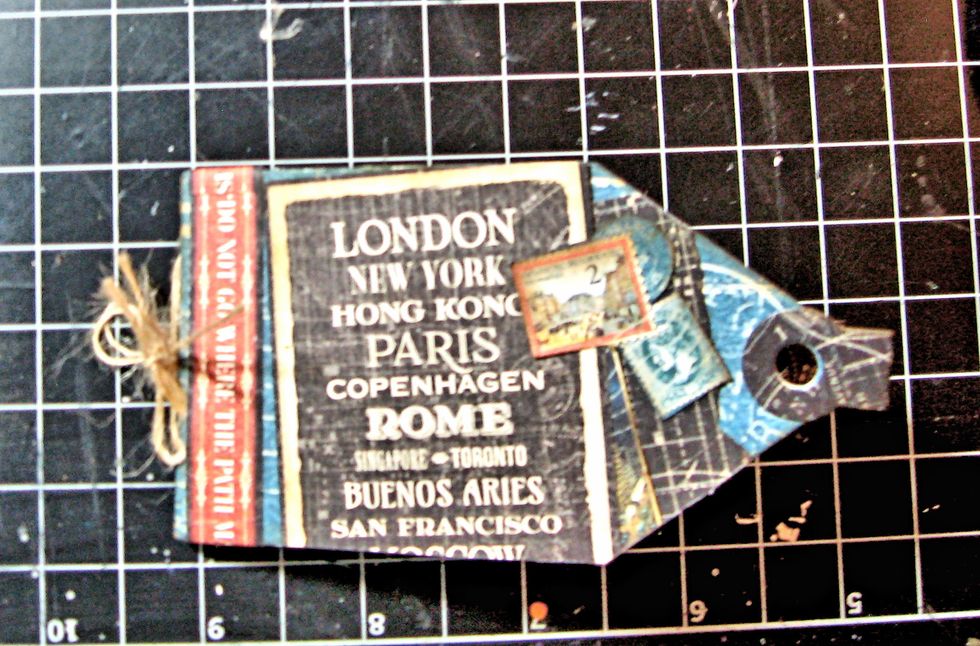 Glue fussy cut stamps to the travel poster from the 8x8 paper. Glue all onto front cover of mini tag book,