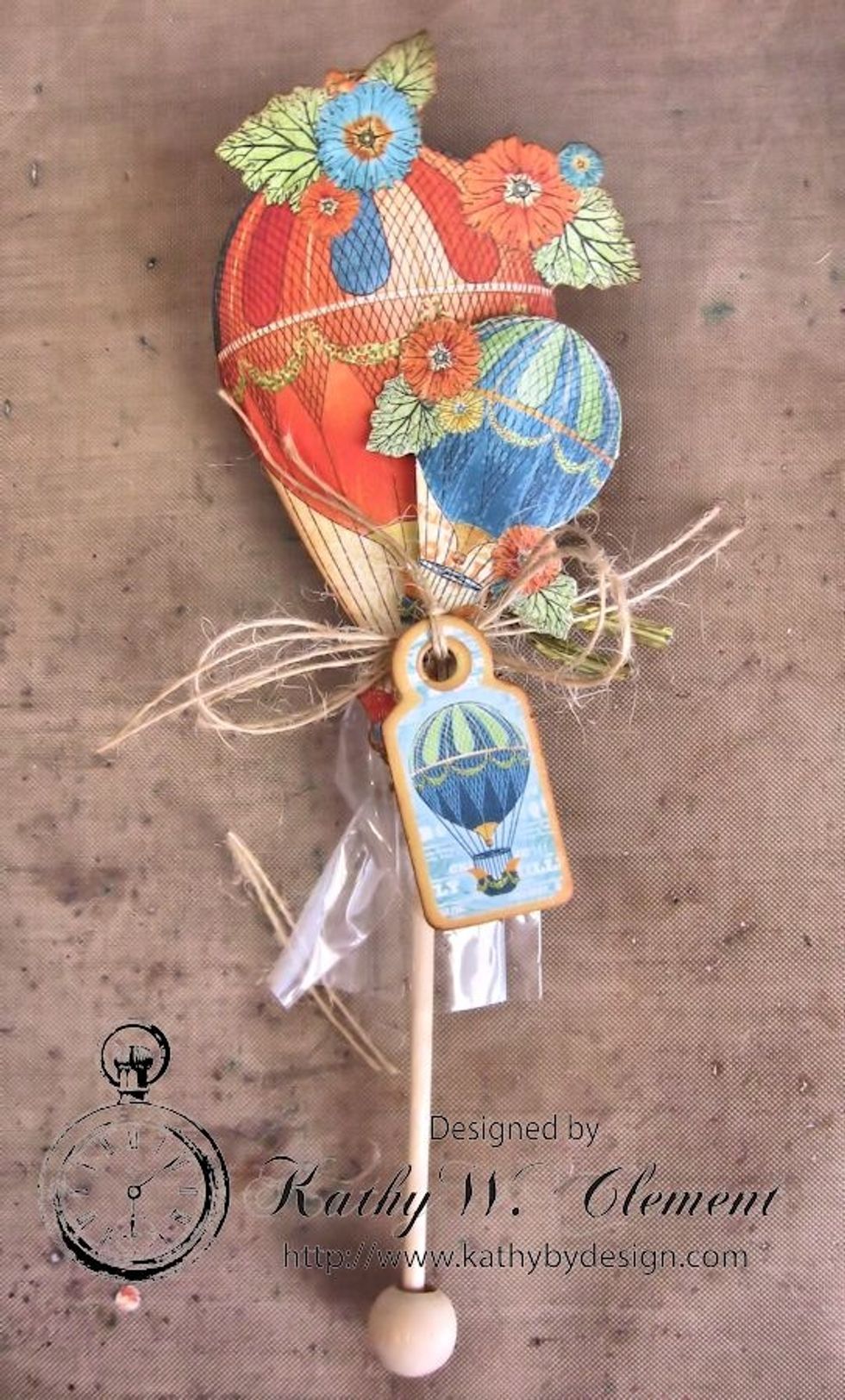 Glue hot air balloons and chipboard to the top of the honey spoon.  Tie with burlap string and insert into pocket.