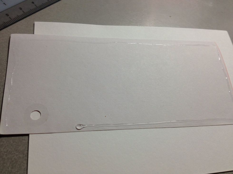 Glue on all borders of the paper, except near the hole. Stick onto card.