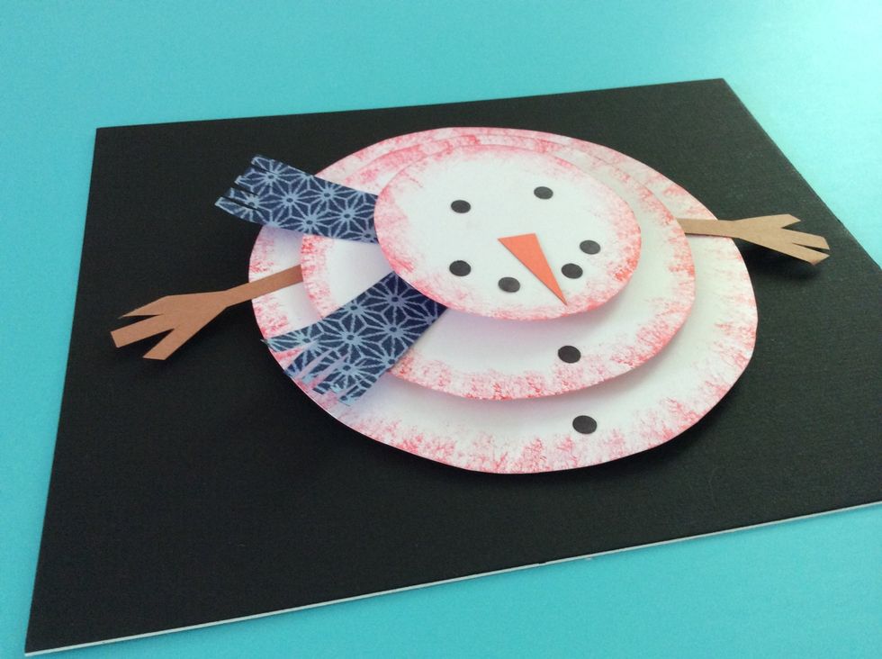 Glue orange nose and black dots to the top of the snowman.